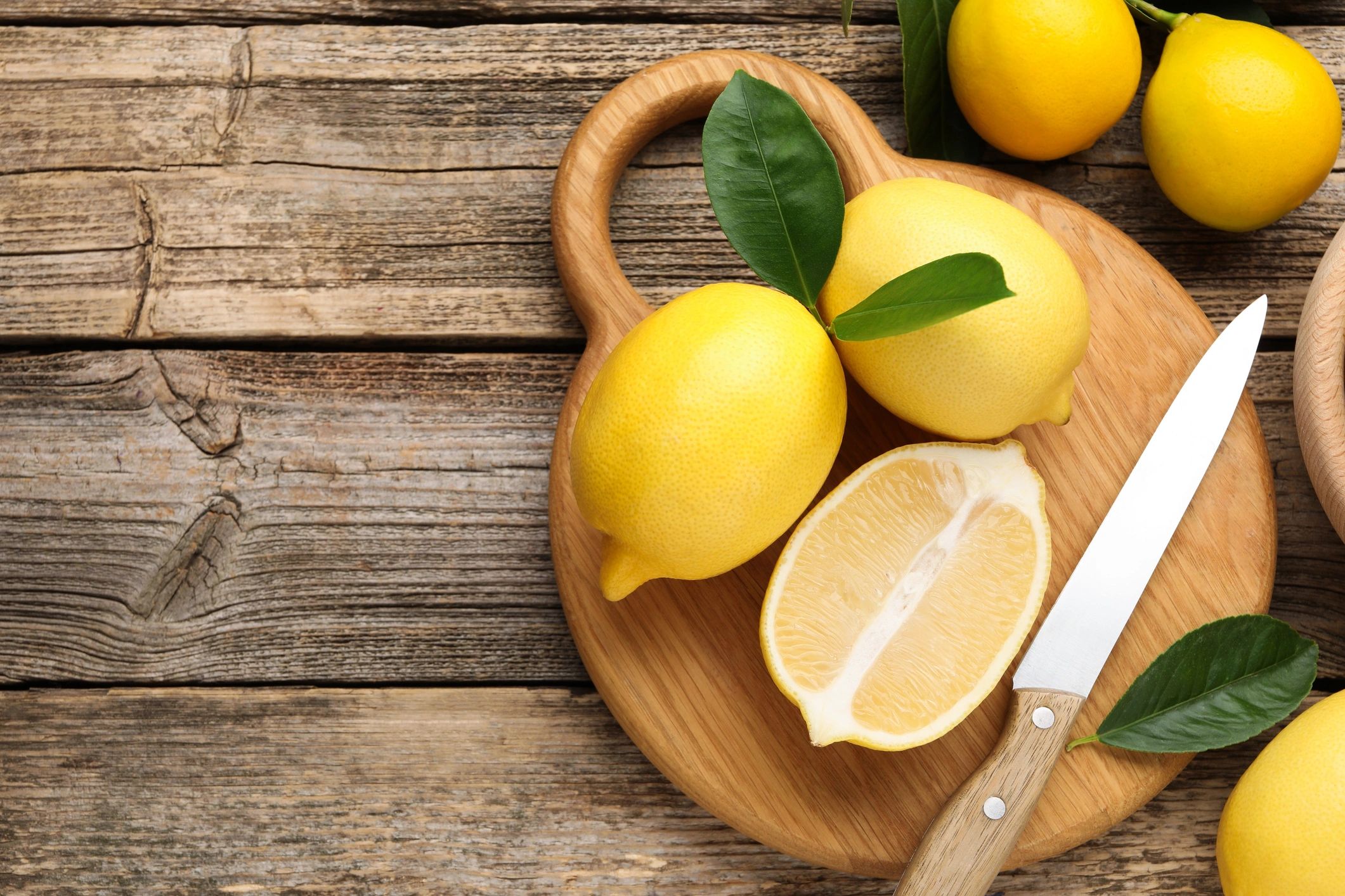Whole and cut lemons on a wooden table